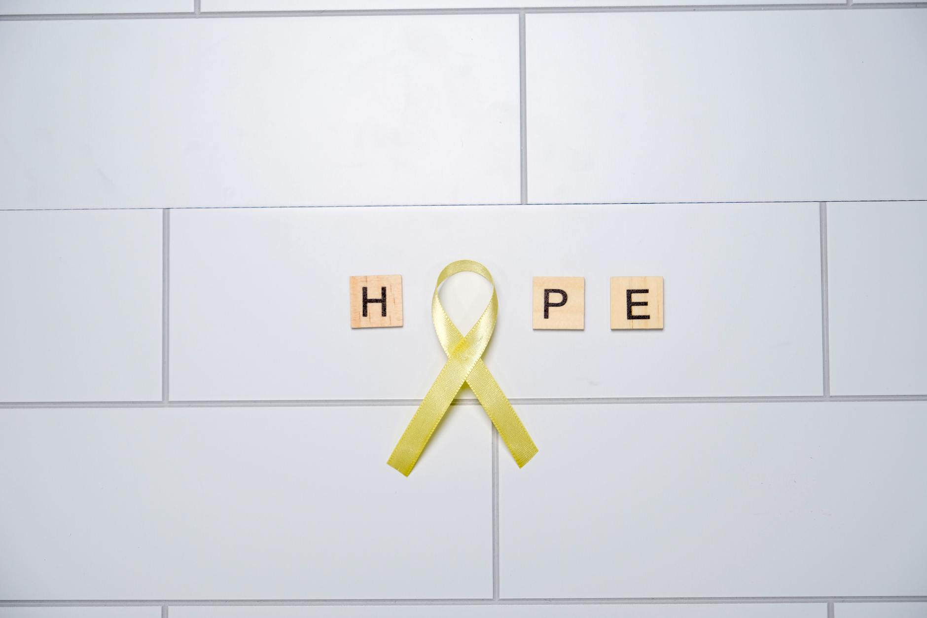 yellow ribbon symbolizing hope on white tiles