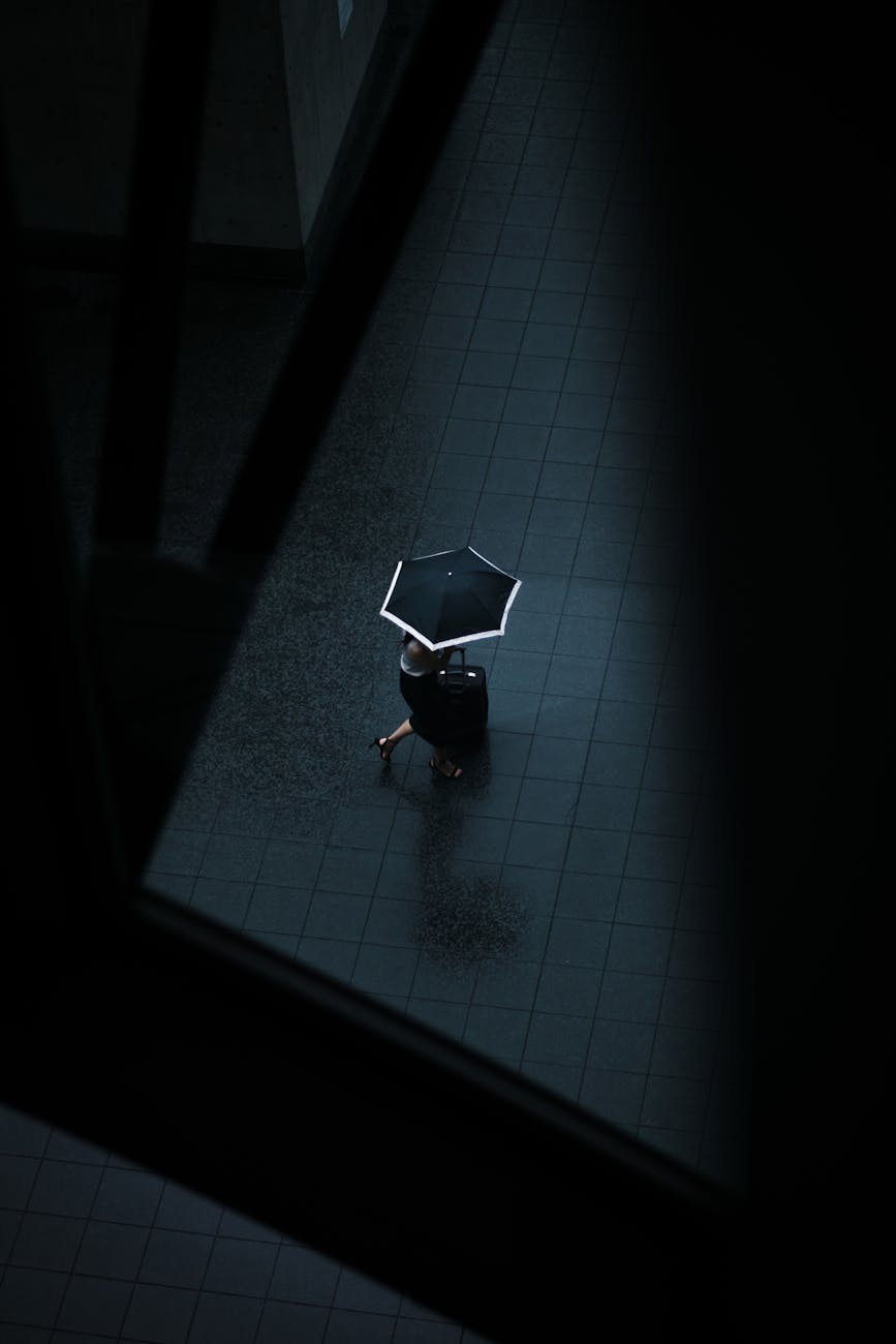 faceless woman walking with umbrella and suitcase