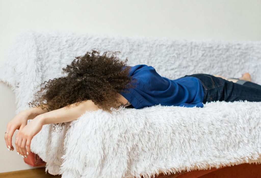 woman wearing blue shirt lying on white couch